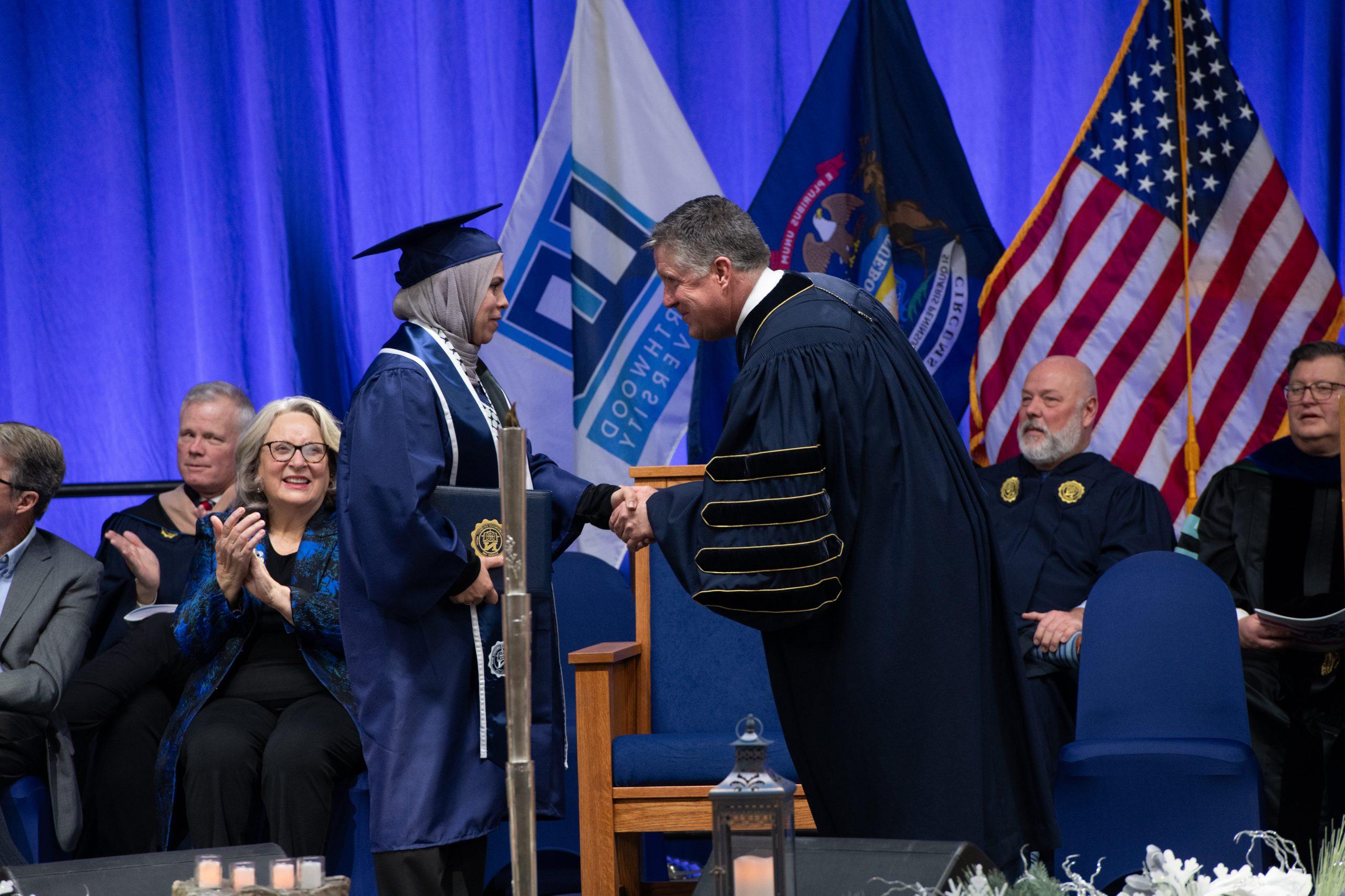Northwood graduate on stage shaking hands with the President after accepting diploma